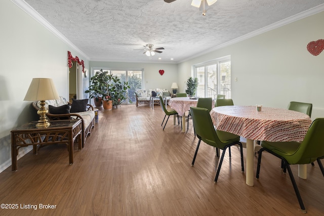 dining room featuring wood-type flooring, a textured ceiling, ceiling fan, and crown molding