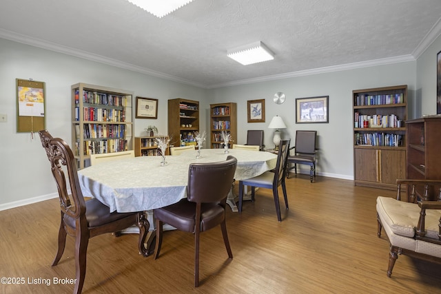 dining area featuring wood-type flooring, ornamental molding, and a textured ceiling