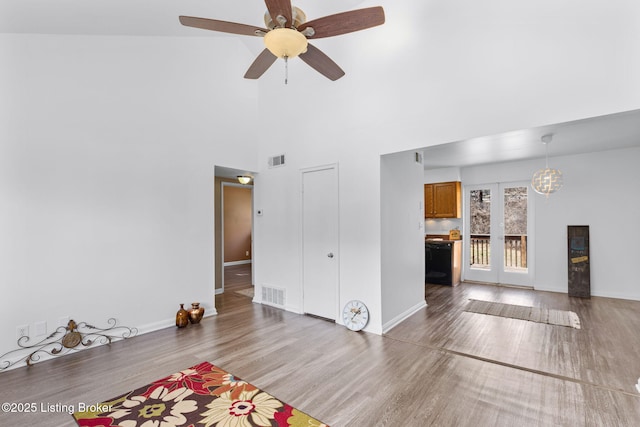 unfurnished living room featuring hardwood / wood-style flooring, ceiling fan, and a high ceiling