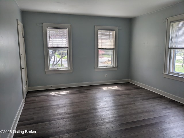 spare room with dark wood-style floors, plenty of natural light, and baseboards