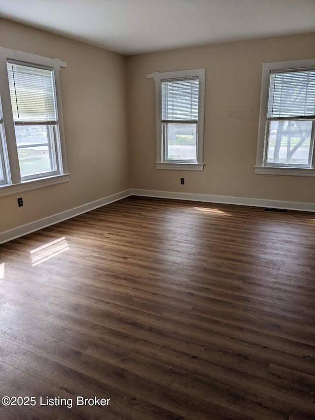 empty room with dark wood-style flooring and baseboards