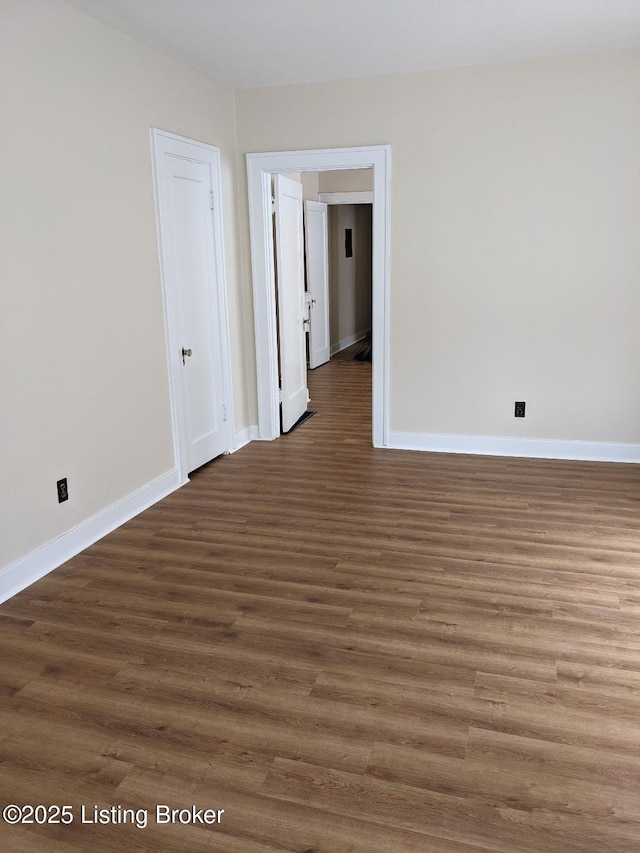 spare room featuring baseboards and wood finished floors