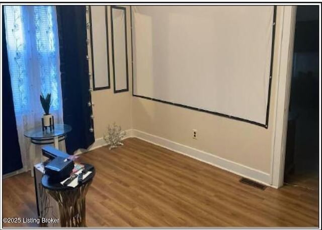 cinema room with visible vents, baseboards, and wood finished floors