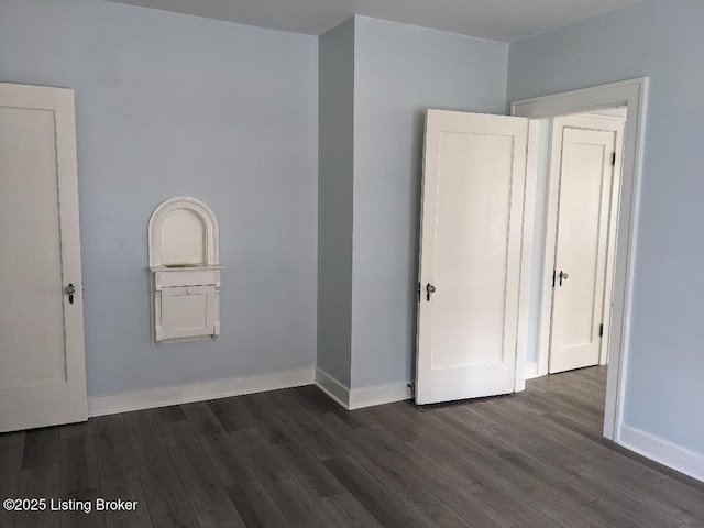 unfurnished bedroom with dark wood-type flooring and baseboards