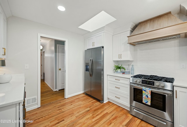 kitchen featuring appliances with stainless steel finishes, custom exhaust hood, and white cabinets