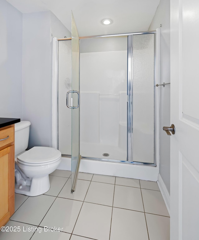 bathroom with tile patterned floors, a stall shower, toilet, and vanity