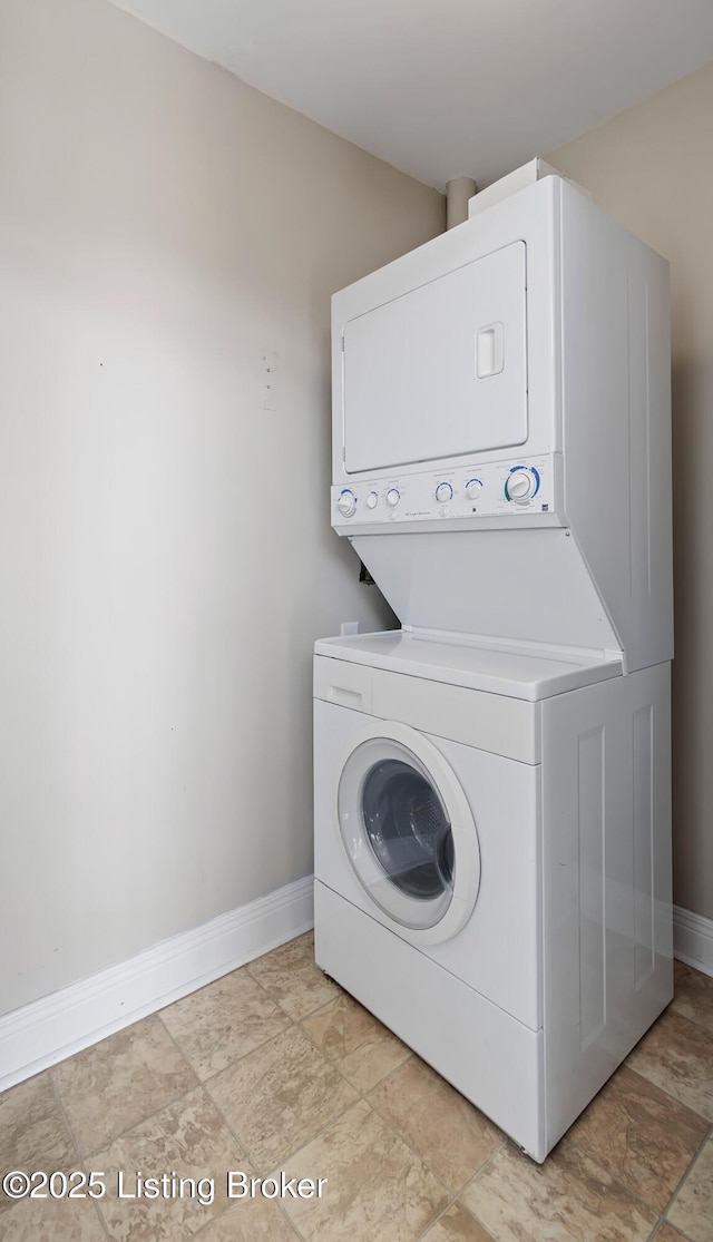 laundry room featuring stacked washer / dryer and baseboards