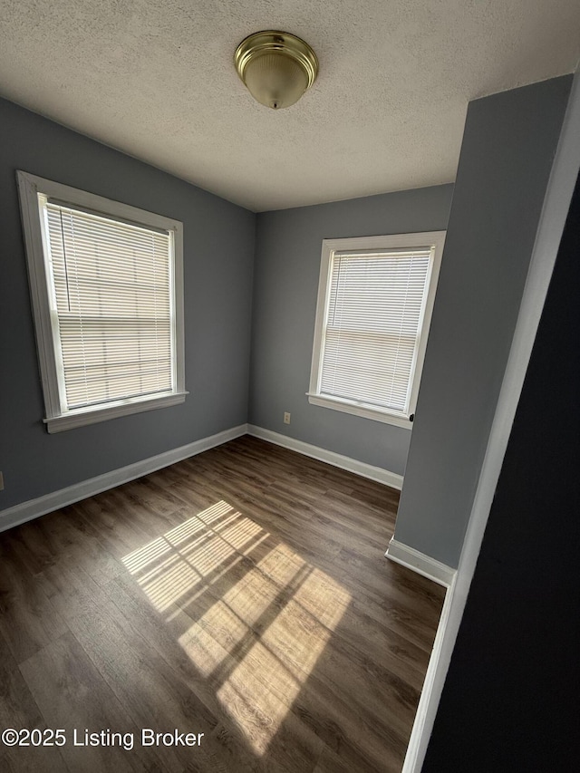 unfurnished room with a textured ceiling, baseboards, and dark wood-type flooring