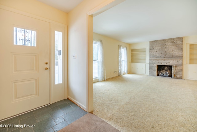 carpeted foyer featuring a stone fireplace and a wealth of natural light