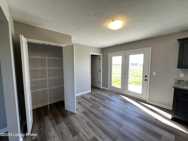 unfurnished bedroom featuring access to exterior, dark wood-type flooring, a closet, and a textured ceiling