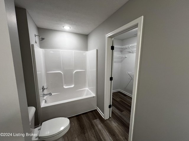 bathroom with hardwood / wood-style floors, toilet, a textured ceiling, and washtub / shower combination