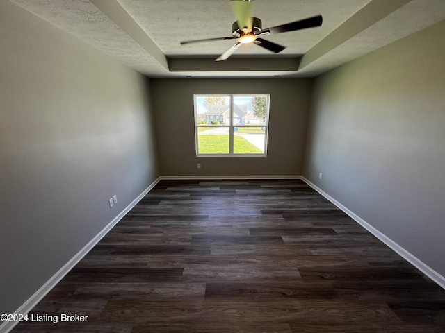 spare room featuring ceiling fan, a tray ceiling, dark hardwood / wood-style floors, and a textured ceiling