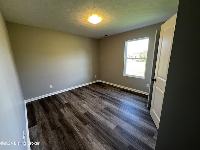 empty room featuring dark hardwood / wood-style flooring and a textured ceiling