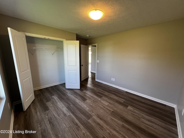 unfurnished bedroom with dark hardwood / wood-style floors, a closet, and a textured ceiling