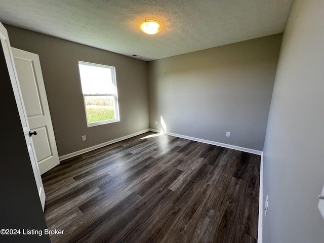 empty room with dark hardwood / wood-style flooring and a textured ceiling