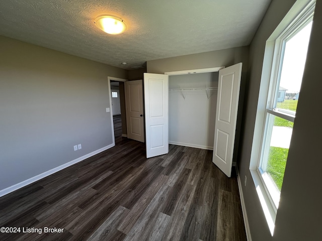 unfurnished bedroom with dark hardwood / wood-style flooring, a closet, and a textured ceiling