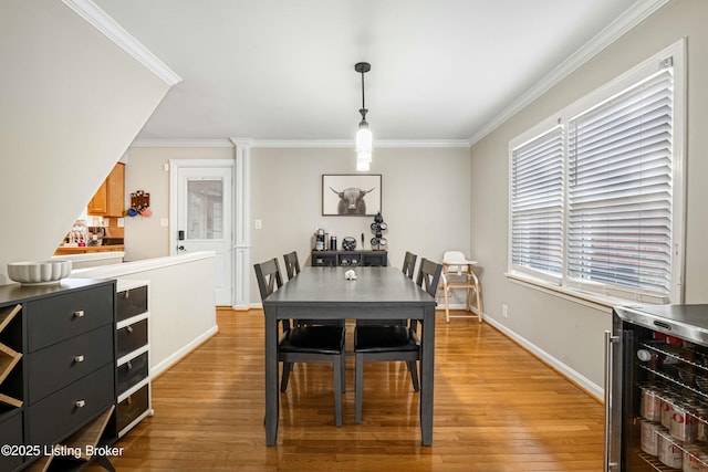 dining area with crown molding, beverage cooler, and light hardwood / wood-style flooring