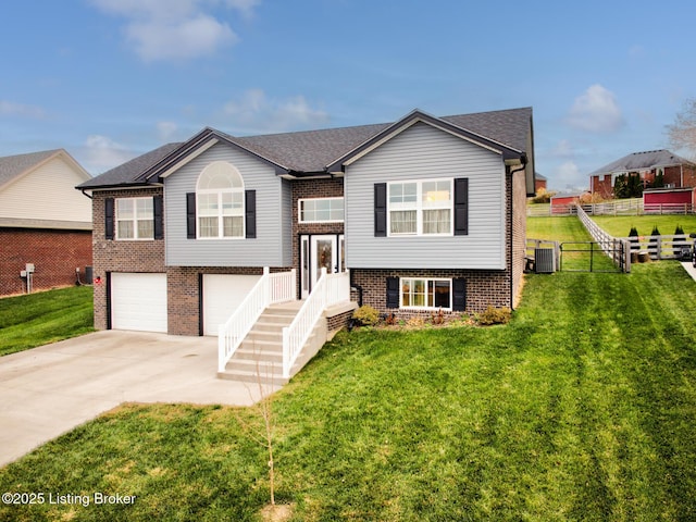 bi-level home with cooling unit, a garage, and a front yard