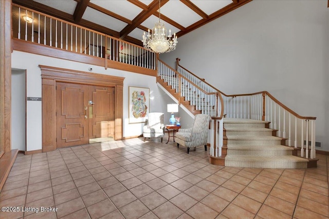 foyer entrance featuring a chandelier, a high ceiling, coffered ceiling, light tile patterned floors, and beam ceiling