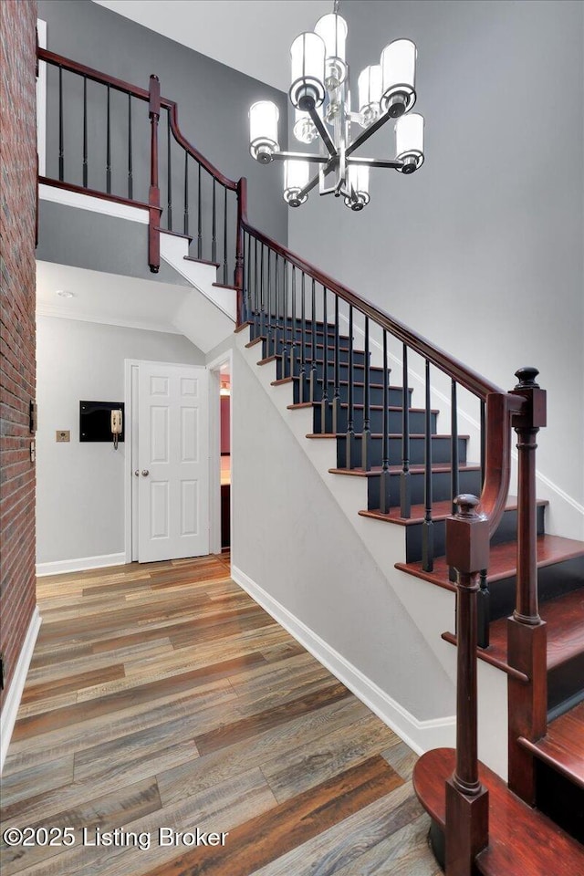 stairway with brick wall, wood-type flooring, and a high ceiling