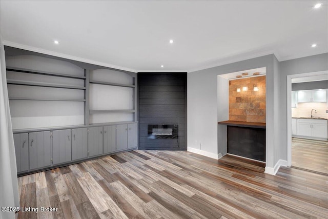 unfurnished living room with hardwood / wood-style flooring, sink, and a large fireplace