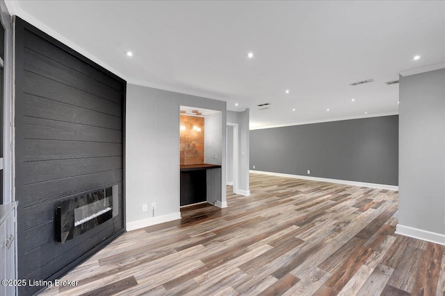 unfurnished living room featuring crown molding and light wood-type flooring