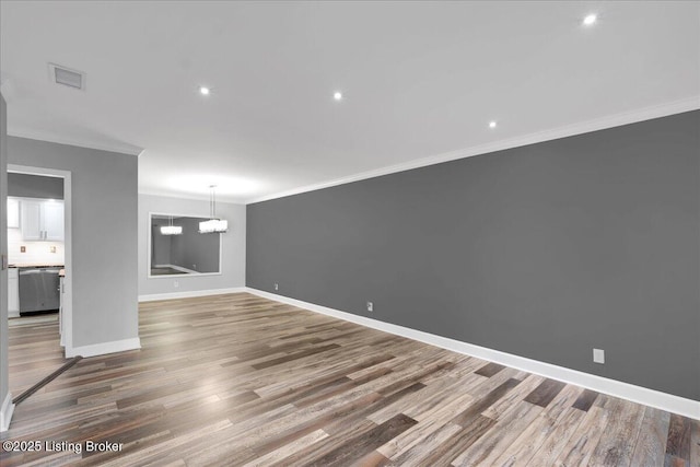 empty room with crown molding, hardwood / wood-style floors, and an inviting chandelier