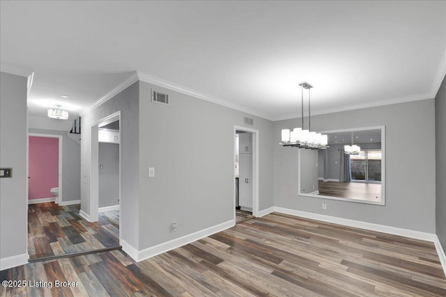 spare room with ornamental molding, dark hardwood / wood-style floors, and a chandelier