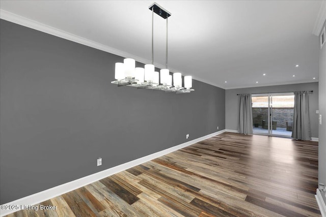 unfurnished dining area with hardwood / wood-style flooring, crown molding, and a notable chandelier