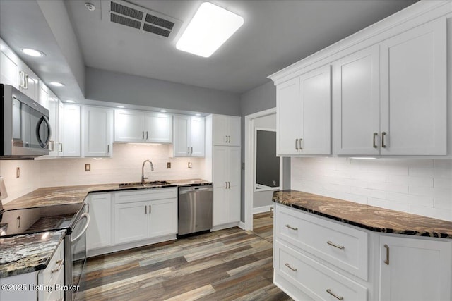 kitchen featuring appliances with stainless steel finishes, hardwood / wood-style floors, white cabinetry, sink, and decorative backsplash