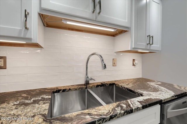 kitchen featuring white cabinets, sink, decorative backsplash, and dark stone countertops