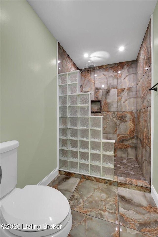 bathroom with a tile shower and toilet