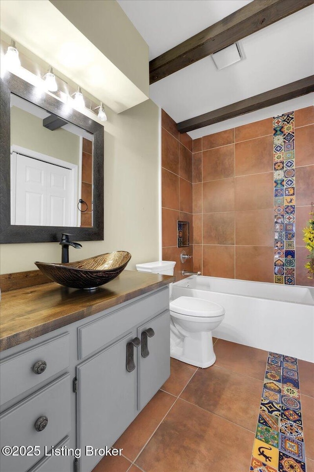 full bathroom with toilet, tiled shower / bath, vanity, beam ceiling, and tile patterned flooring