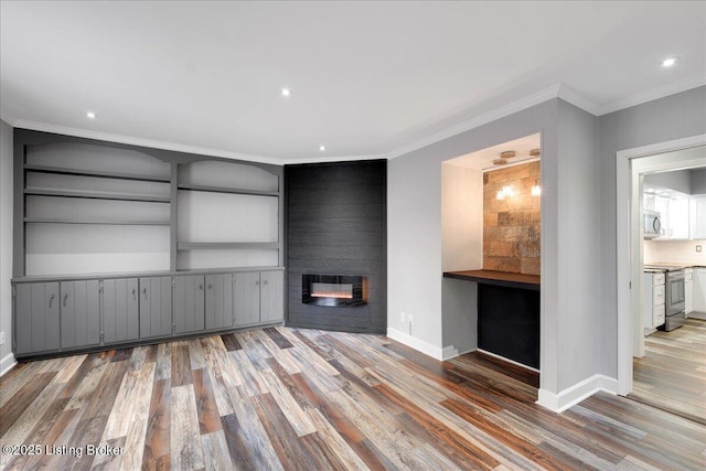 unfurnished living room with hardwood / wood-style floors, ornamental molding, and a large fireplace