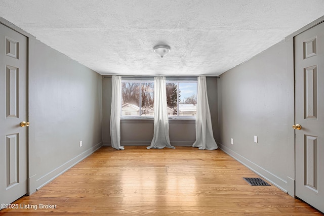 spare room with light hardwood / wood-style flooring and a textured ceiling