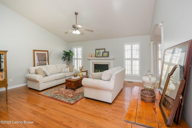 living room with a fireplace, a wealth of natural light, light hardwood / wood-style flooring, and ornate columns