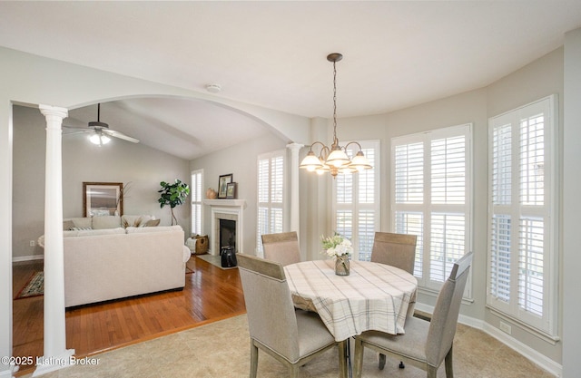 dining room with ceiling fan with notable chandelier, vaulted ceiling, and ornate columns