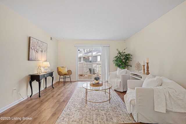 living room with light wood finished floors, visible vents, and baseboards