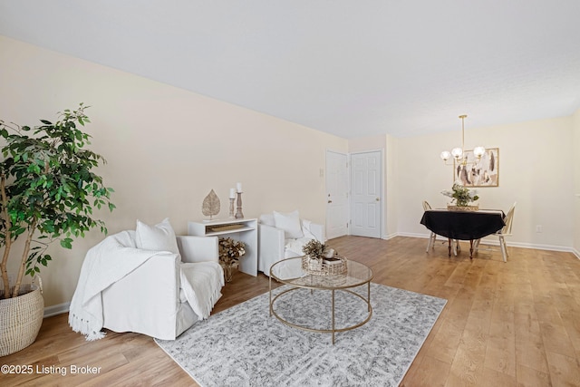 living room featuring a notable chandelier, baseboards, and light wood-style flooring