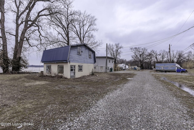 exterior space featuring metal roof, gravel driveway, and a gambrel roof