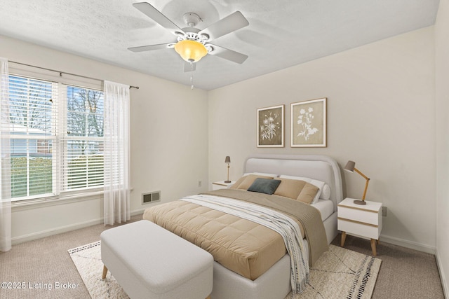 carpeted bedroom featuring ceiling fan and a textured ceiling