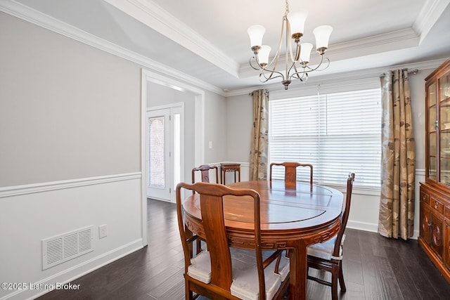 dining room featuring dark hardwood / wood-style flooring, a tray ceiling, ornamental molding, and an inviting chandelier