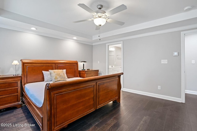 bedroom featuring dark wood-type flooring, ceiling fan, connected bathroom, and a raised ceiling