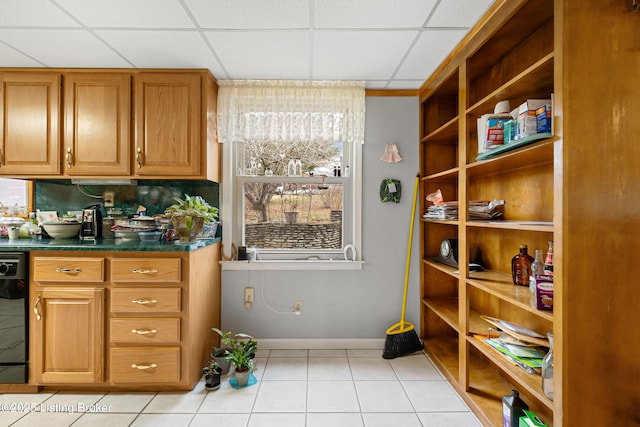 kitchen with light tile patterned floors, a paneled ceiling, and black dishwasher