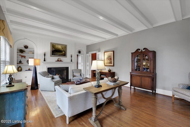 living room with beam ceiling, hardwood / wood-style flooring, and built in shelves