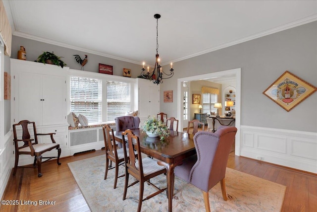 dining space with crown molding, radiator heating unit, an inviting chandelier, and light hardwood / wood-style floors