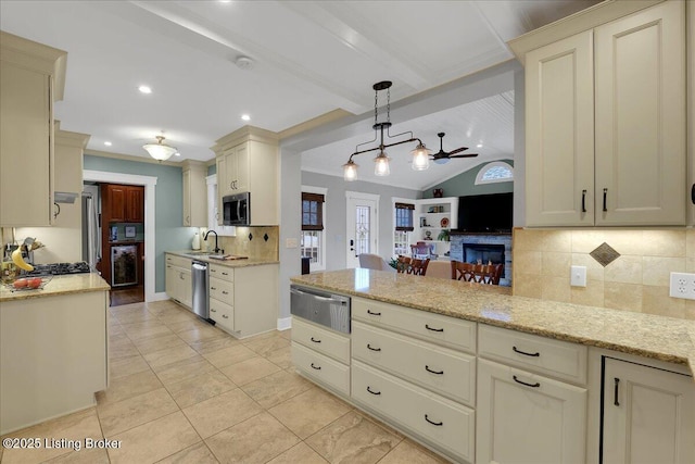 kitchen with decorative light fixtures, sink, backsplash, stainless steel appliances, and cream cabinetry