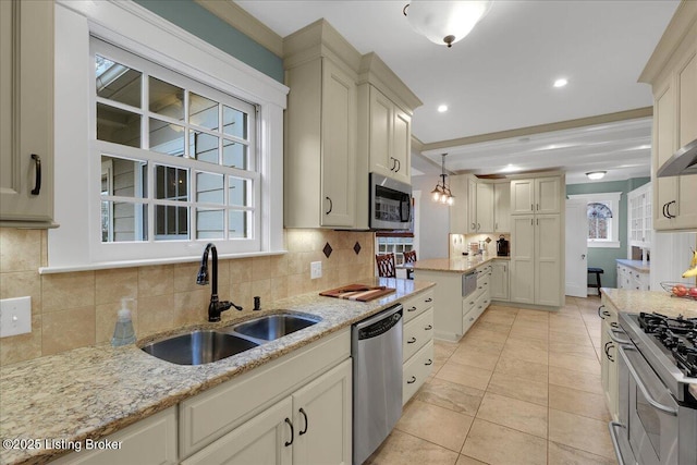 kitchen with sink, light stone counters, decorative light fixtures, stainless steel appliances, and decorative backsplash