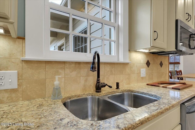 kitchen with stainless steel appliances, light stone countertops, sink, and backsplash