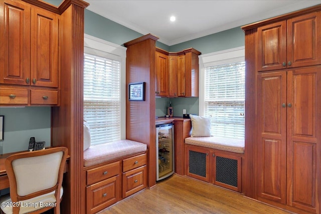 kitchen with plenty of natural light, built in desk, wine cooler, and light hardwood / wood-style floors